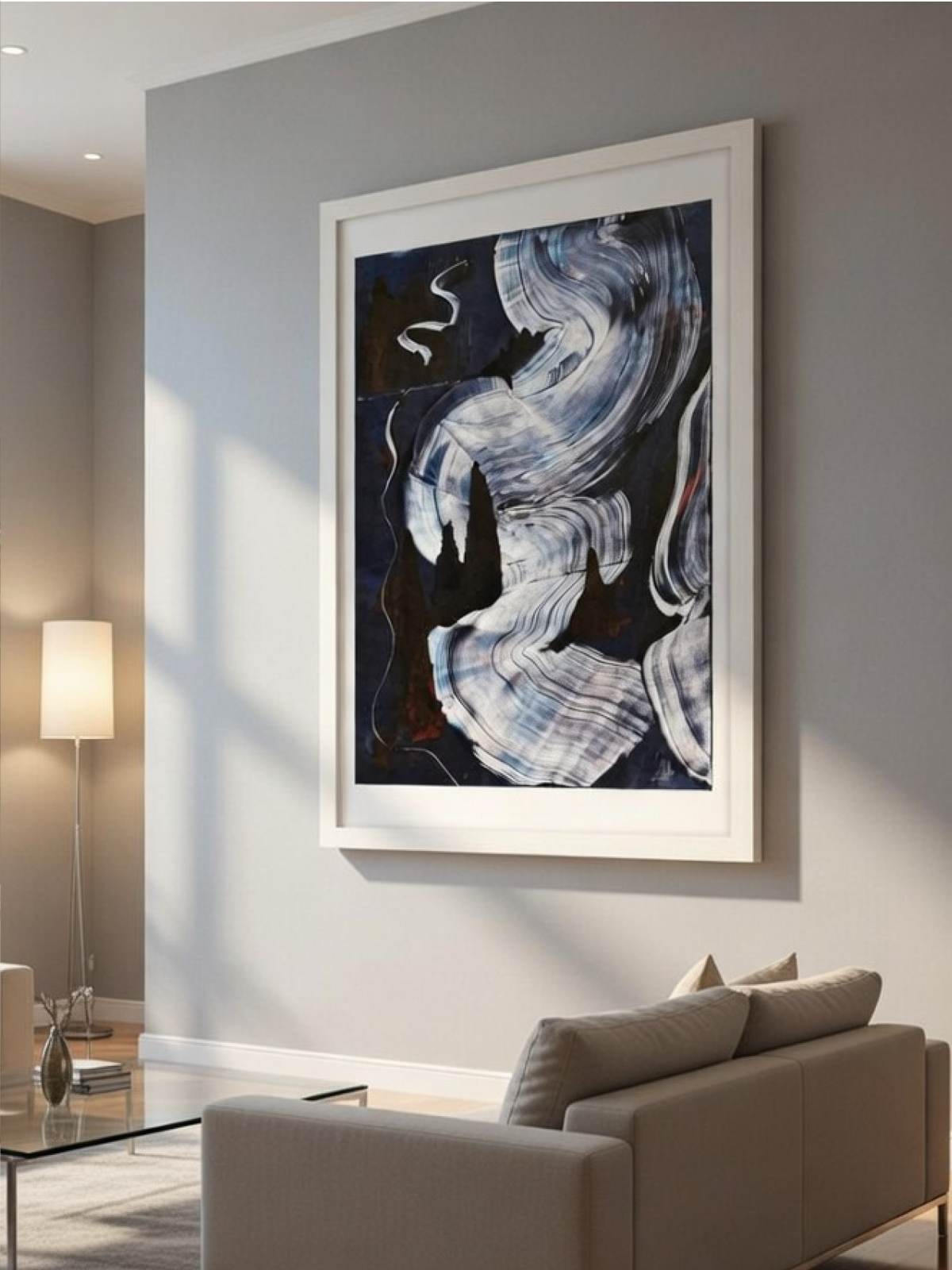 Large white-framed dark blue abstract ripple print hanging on a gray wall in a minimalist, sunlit living room.