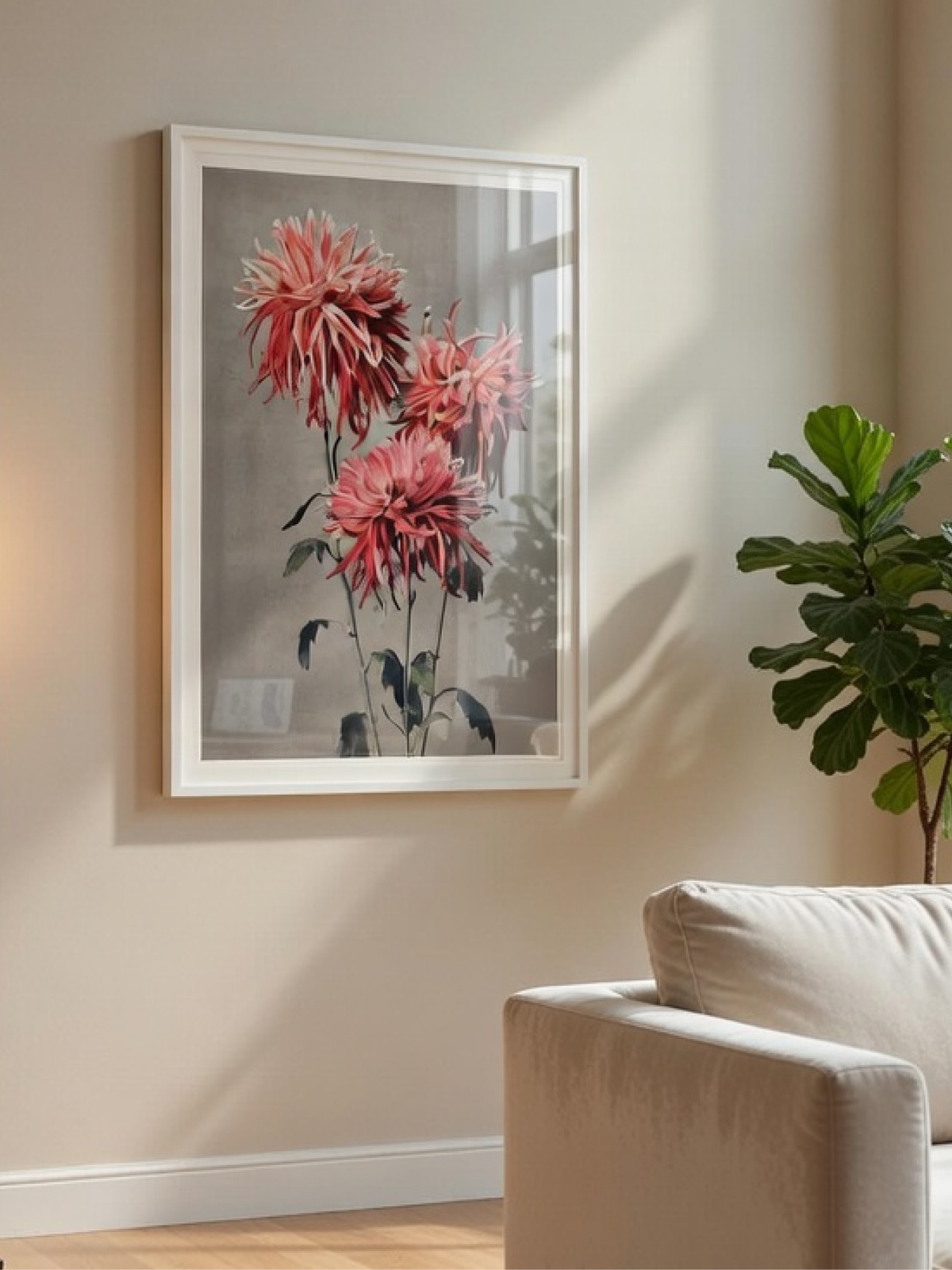 White-framed art print of pink chrysanthemum flowers on a neutral wall in a sunlit interior room.