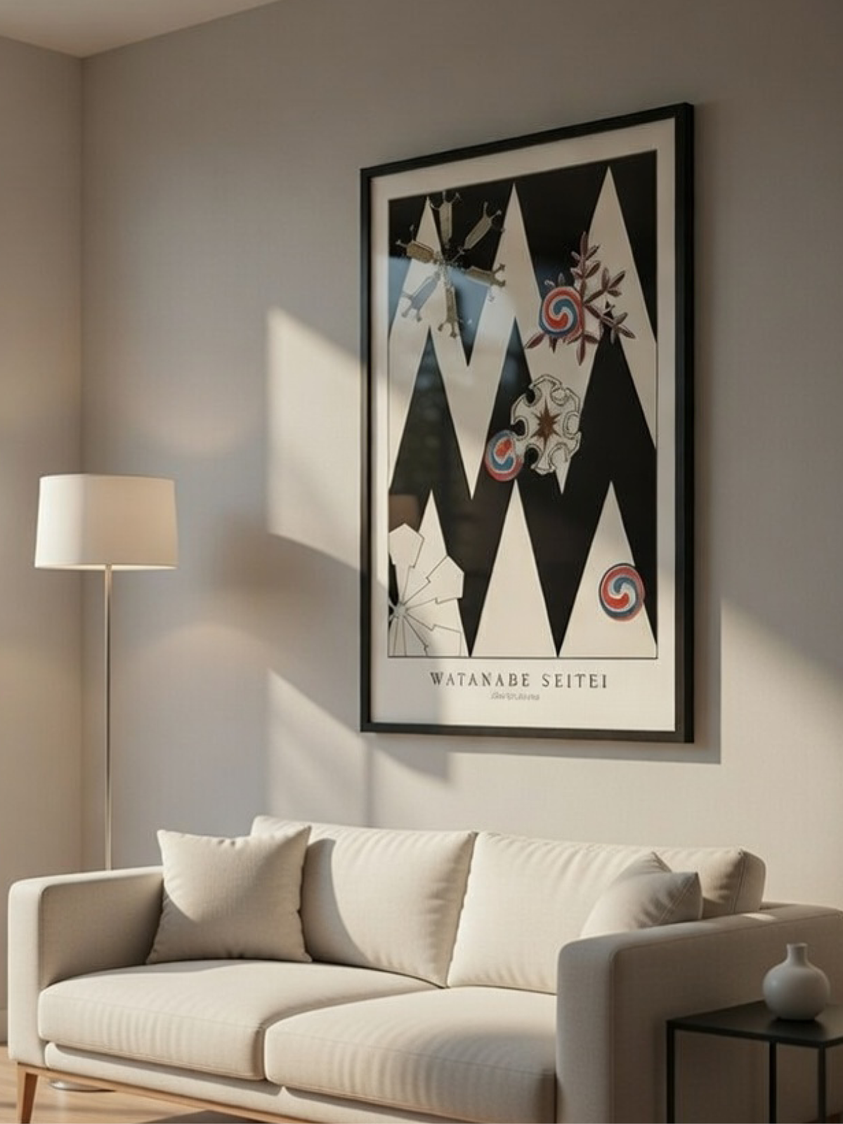Black-framed Watanabe Seitei graphic exhibition poster above a modern cream sofa in a sunlit room.