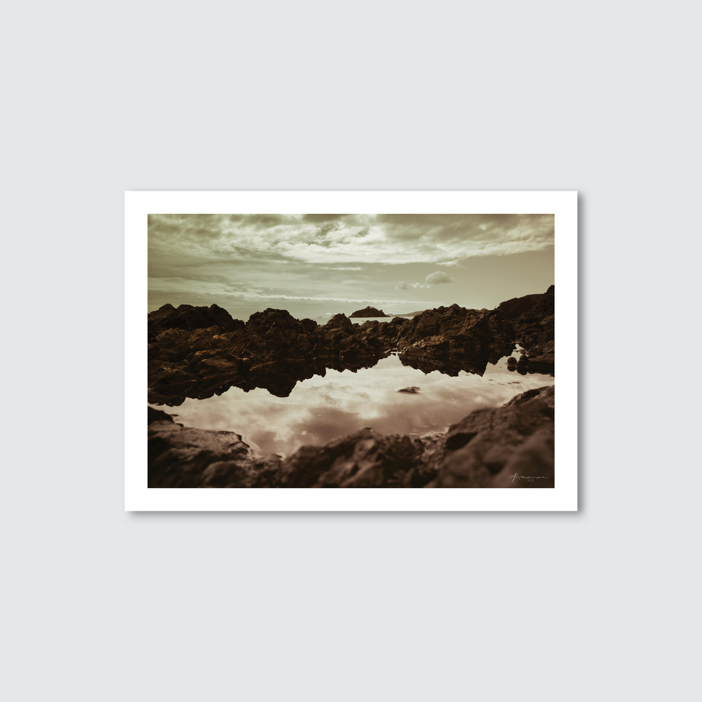 Framed photograph of a rocky landscape with water reflection on a light gray background