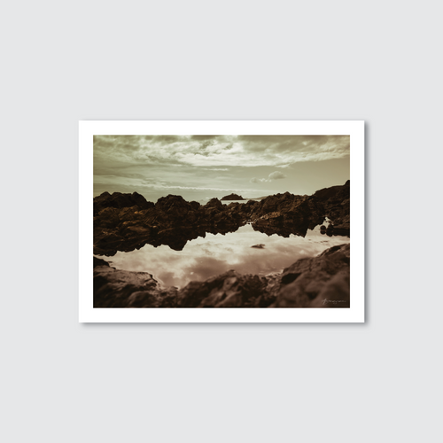 Framed photograph of a rocky landscape with water reflection on a light gray background