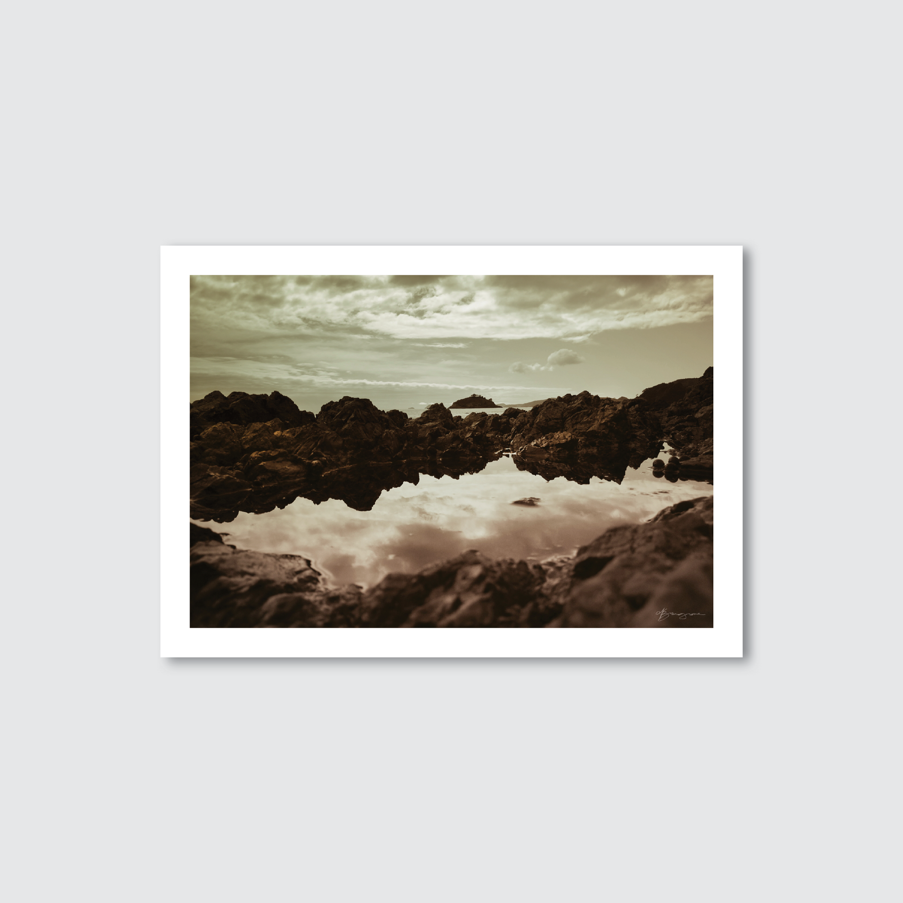 Framed photograph of a rocky landscape with water reflection on a light gray background