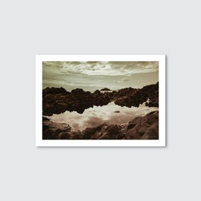 Framed photograph of a rocky landscape with water reflection on a light gray background