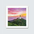 Framed artwork of a lighthouse North Island New Zealand Cape Reinga on a hill with a colourful sunset sky.