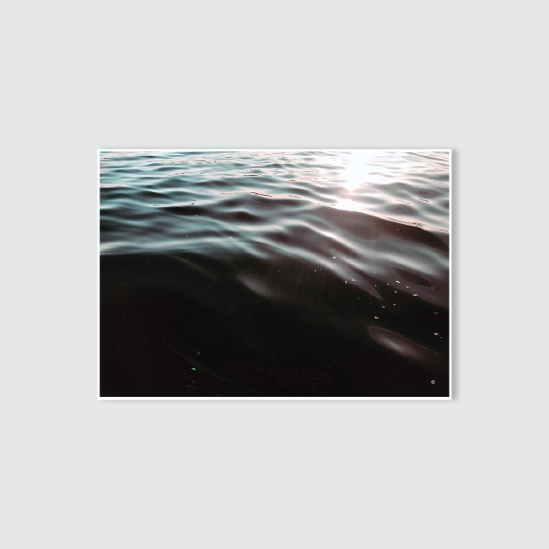 A serene photograph of a body of water with light reflections on the surface, converted into a black and white image.
