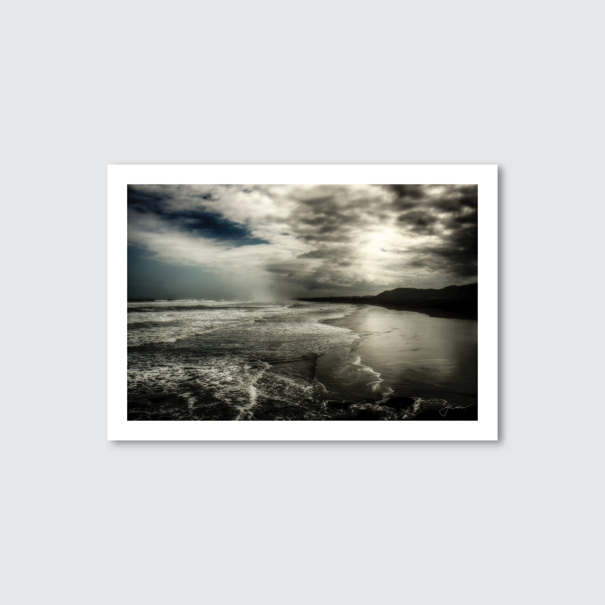 Framed photograph of a landscape with a body of water and mountains under a cloudy sky.