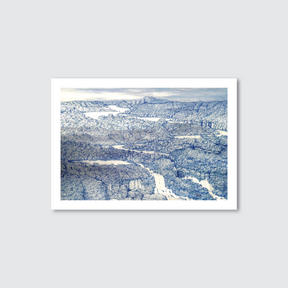 Framed artwork of a snowy landscape with mountains and roads.